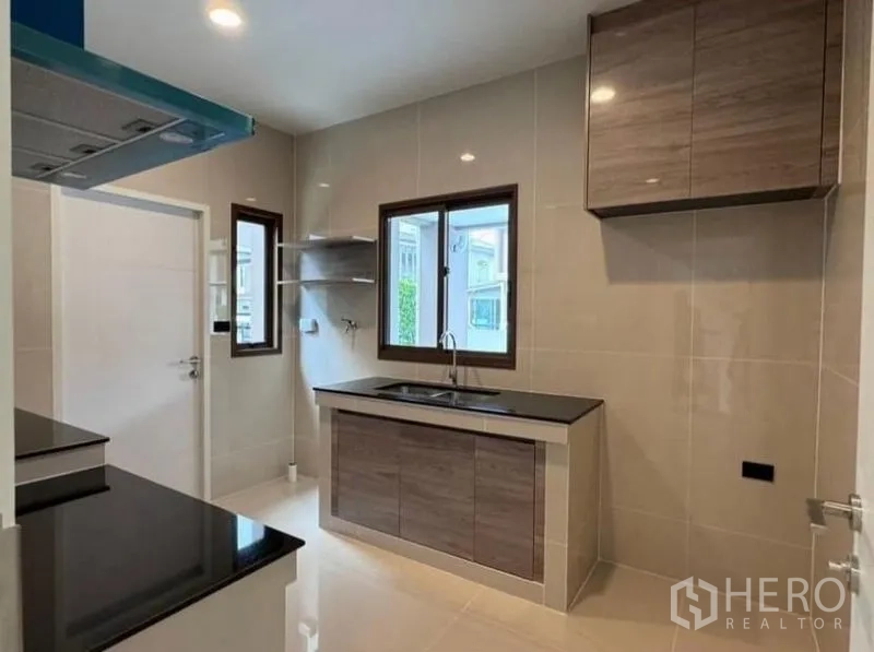 Detached House for rent in Bang Kapi, Bangkok - Separate Thai kitchen with windows, shelving and twin black stone counters.