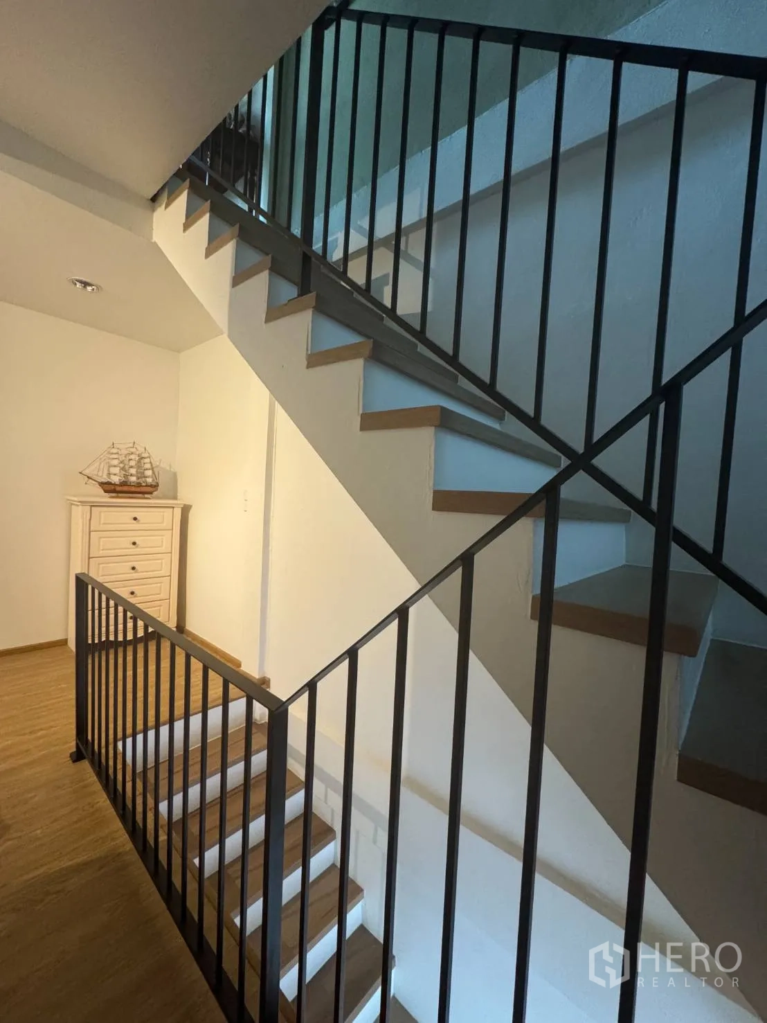 Shophouse for sale in Watthana, Bangkok - Switchback staircase with black balustrade and wooden treads.