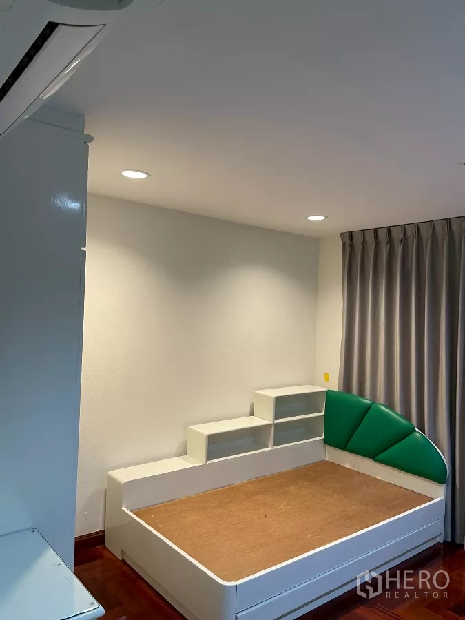 คอนโด ขายในWatthana, Bangkok - ห้องนอนรอง เตียงเดี่ยวพนักพิงสีเขียว ชั้นวางของ และผ้าม่านทึบ