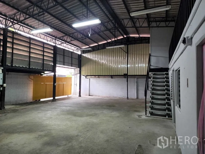 货栈 出租在Chatuchak, Bangkok - 清爽装卸空间，面向金属入口门与带楼梯的抬高平台。