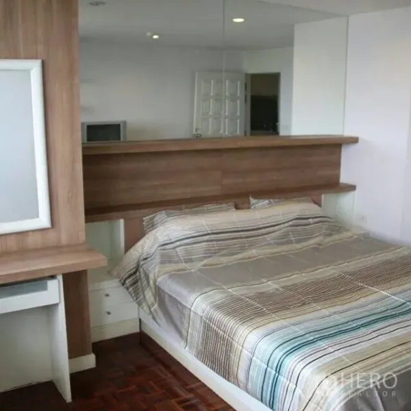 Condominium for rent in Watthana, Bangkok - Master bedroom featuring a wood headboard, built-in desk and a mirrored wall.