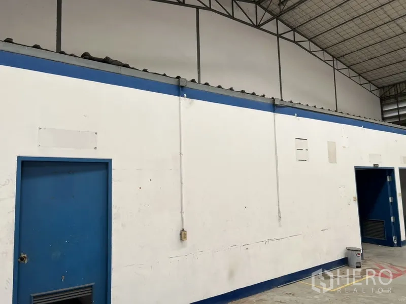 Warehouse for rent in Suan Luang, Bangkok - Warehouse interior with white walls, blue doors and a high steel truss roof.