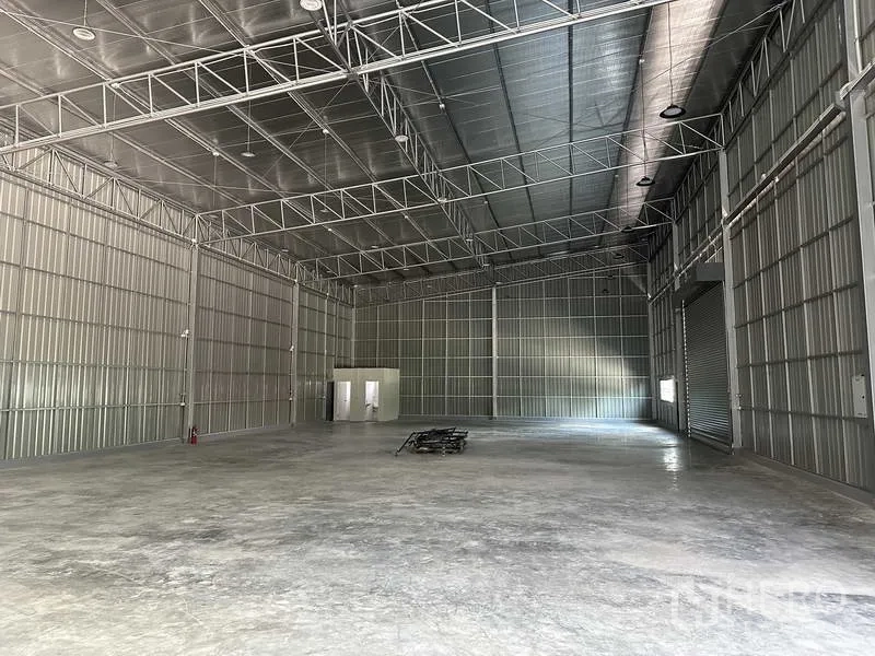 Warehouse for rent in Pak Kret, Nonthaburi - Spacious warehouse interior with high steel truss roof, polished concrete floor and roller door.