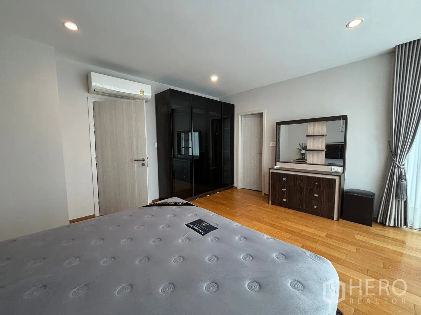 Townhouse for rent in Saphan Sung, Bangkok - Bedroom with bed, glossy black wardrobe, dressing table, and curtains.
