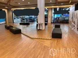 零售空间 出租在Khlong Toei, Bangkok - 开放式零售区，木纹地板、中央立柱与座椅，临近商场店面通道，靠近BTS通罗站。