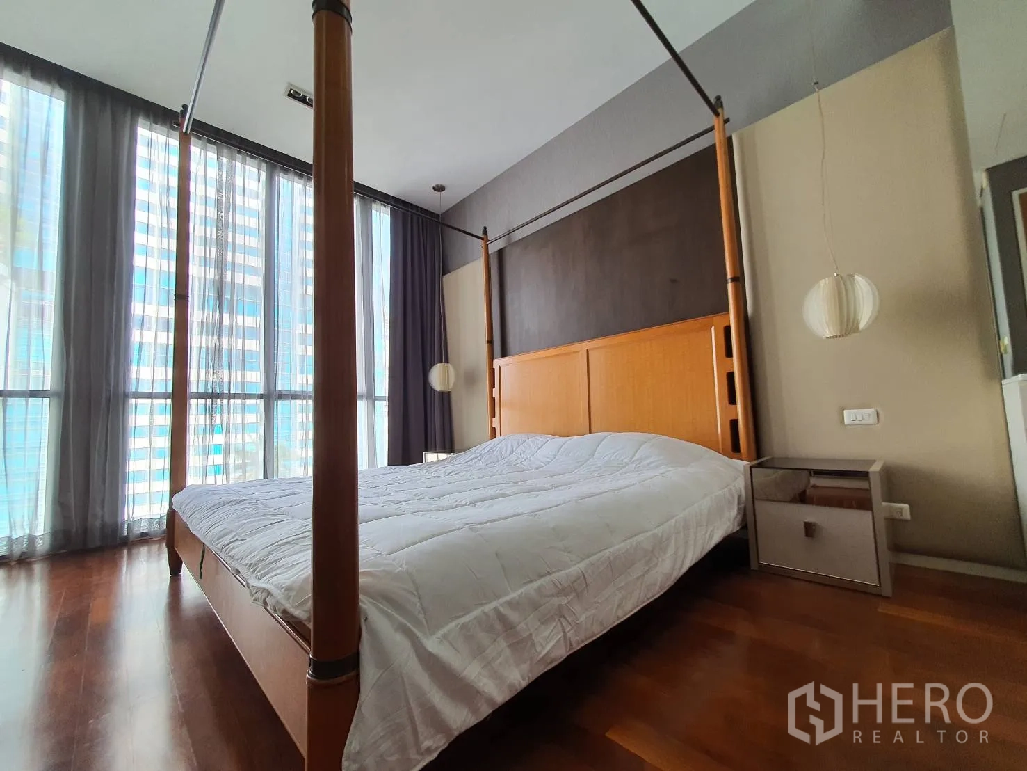 Condominium for rent in Khlong Toei, Bangkok - Four-poster bed beside full-height glazing with sheer curtains and urban outlook.