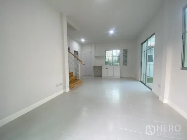 Detached House for sale in Nonthaburi - Spacious living-dining room with tiled floors, staircase and dual sliding doors to the garden.