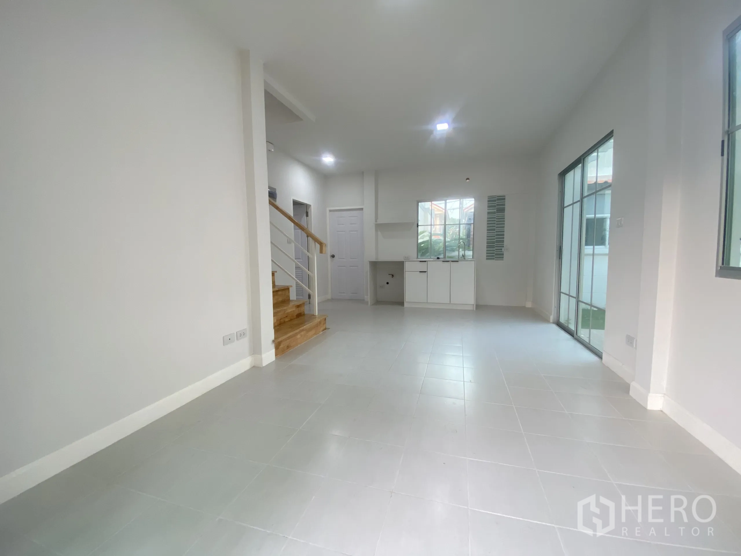 Detached House for sale in Nonthaburi - Spacious living-dining room with tiled floors, staircase and dual sliding doors to the garden.