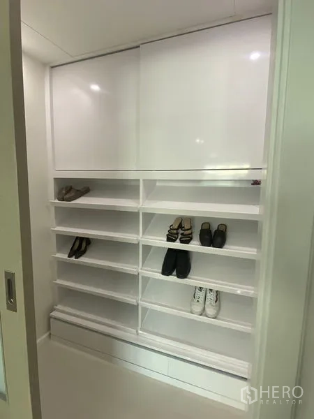 Condominium for rent in Watthana, Bangkok - Built-in white shoe cabinet with multiple shelves and sliding doors.