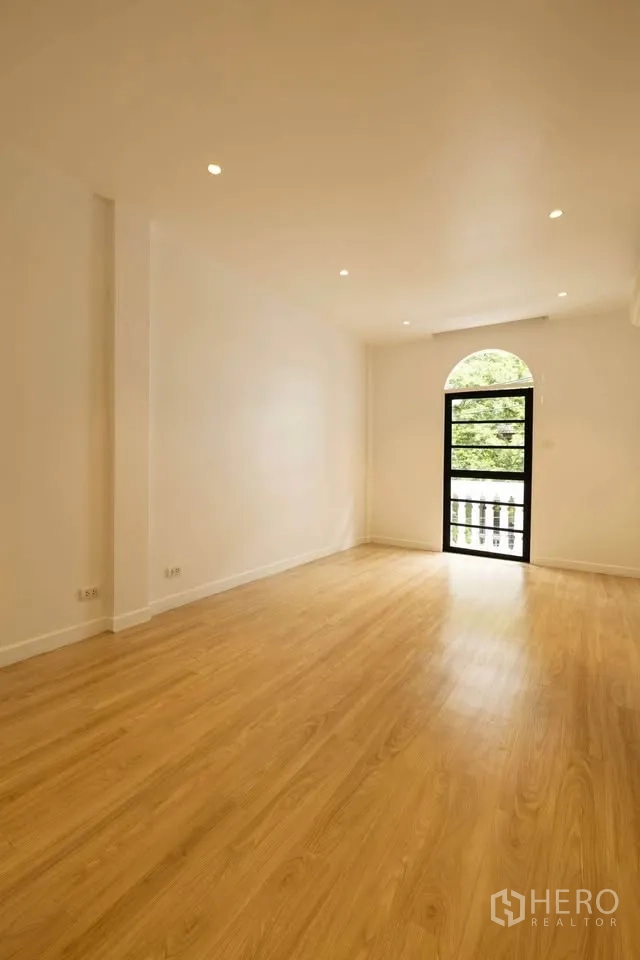 联排别墅 出租在Khlong Toei, Bangkok - 宽阔房间，拱形门通向阳台，可见绿色景观。