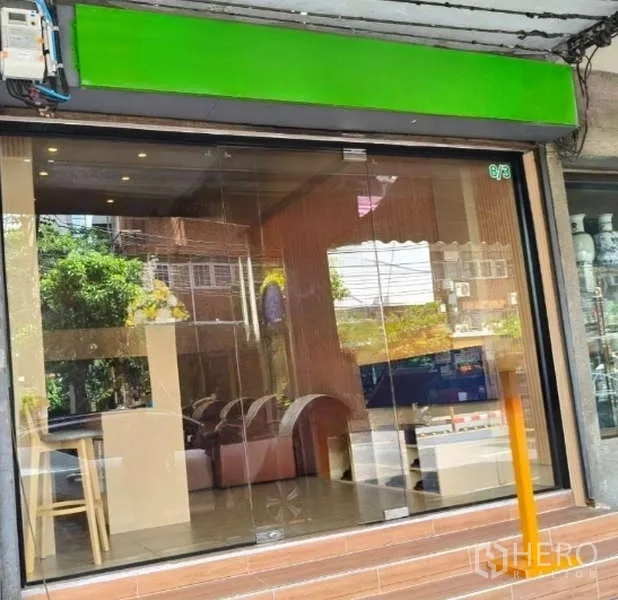店屋 出租或出售在Watthana, Bangkok - 临街玻璃店面，顶部绿色招牌的商铺门头。