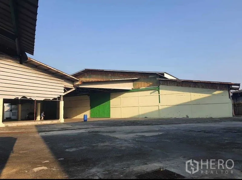 货栈 出租或出售在Mueang Pathum Thani, Pathum Thani - 仓库外立面配绿色推拉大门，场地开阔便于调度。