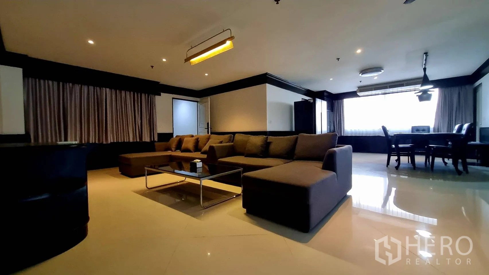 公寓 出租在Watthana, Bangkok - 开放式起居区，大型L形沙发与窗边餐区。