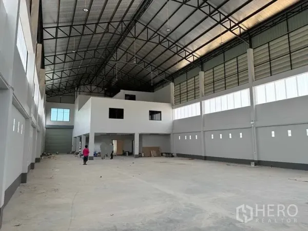 Factory for sale in Khlong Luang, Pathum Thani - Factory interior showing mezzanine office block, large loading roller door and lofty roof structure.