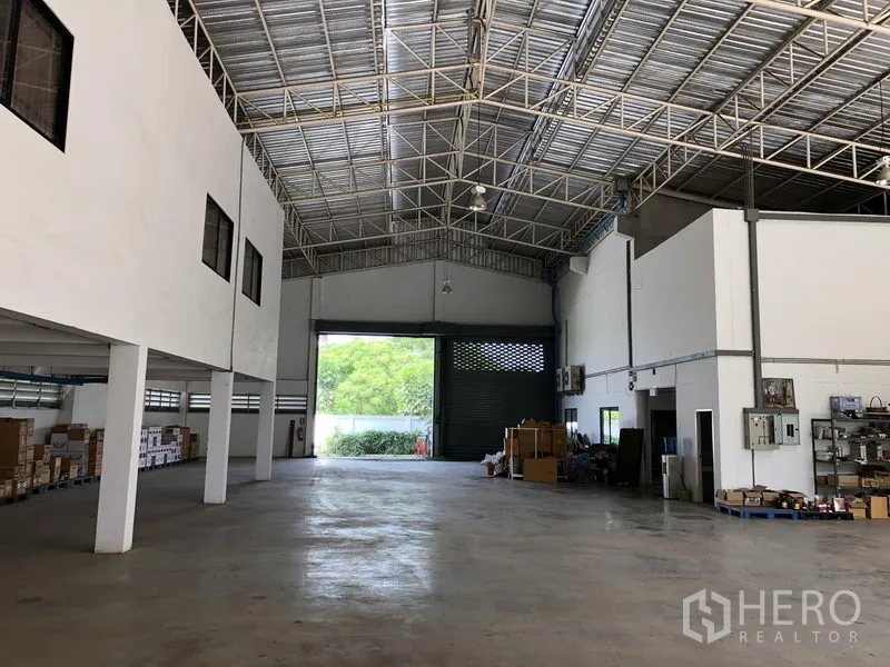 Factory for rent or sale in Lat Lum Kaeo, Pathum Thani - Warehouse hall facing a large loading roller door with storage areas and ceiling lights.