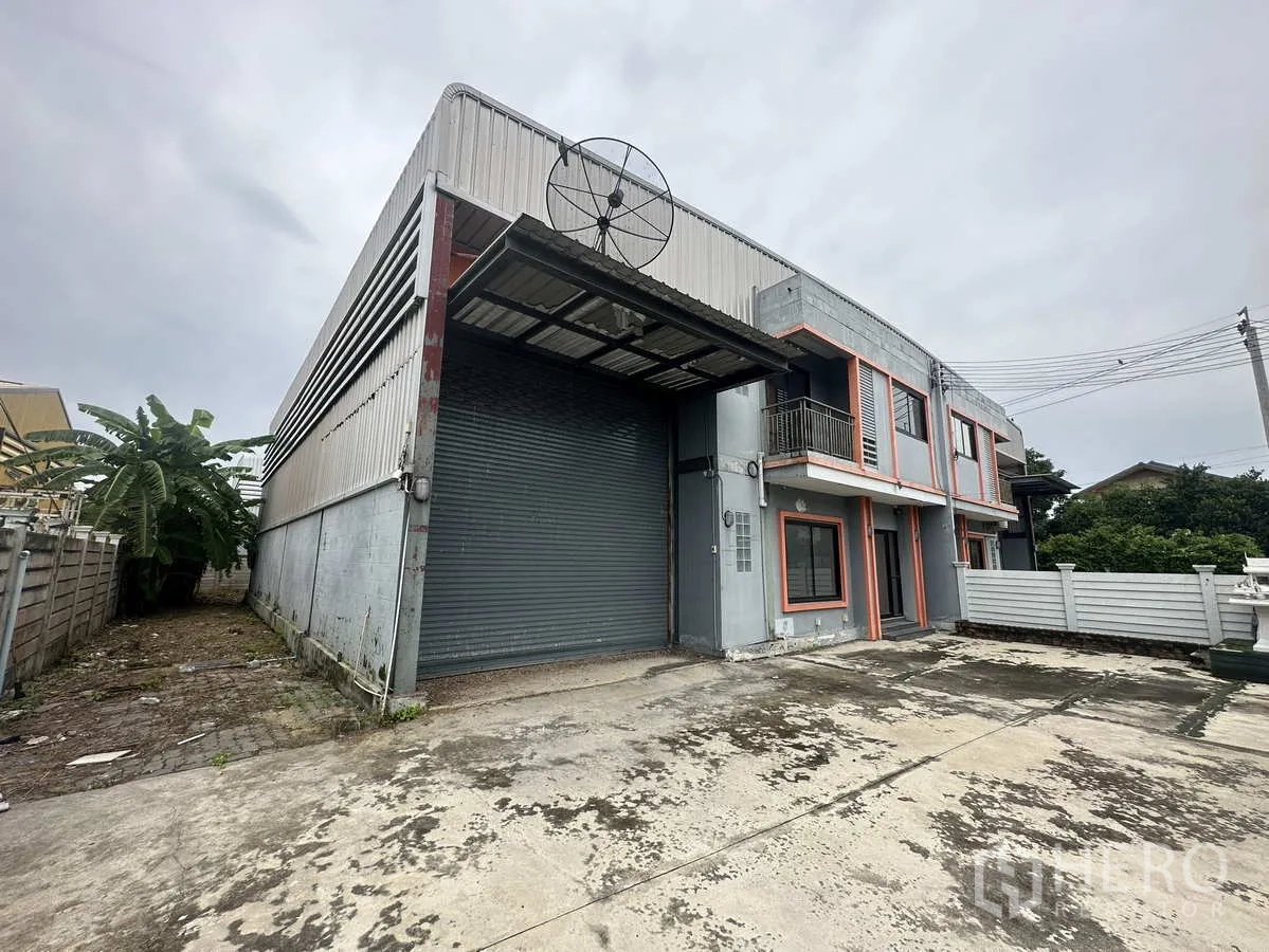 คลังสินค้า ให้เช่าหรือขายในBang Yai, Nonthaburi - มุมมองด้านข้างของโกดัง มีหลังคารองรับขนถ่ายสินค้าและประตูม้วนโลหะ พร้อมทางรถเข้า