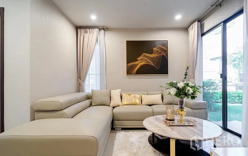 บ้าน ขายในLam Luk Ka, Pathum Thani - ห้องนั่งเล่นอบอุ่น โซฟาเข้ามุม ประตูกระจกบานเลื่อนมองเห็นสวน
