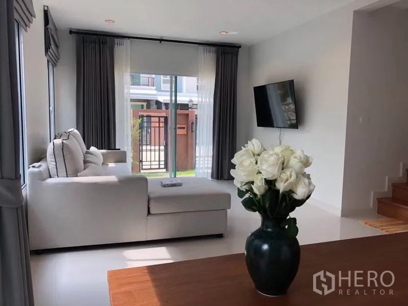 บ้าน ให้เช่าในSuan Luang, Bangkok - ห้องนั่งเล่นสว่างด้วยโซฟาเข้ามุม ประตูกระจกบานเลื่อน และทีวีติดผนัง