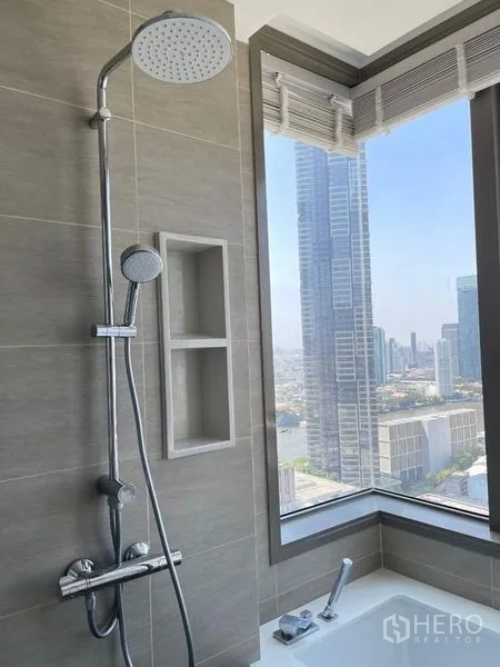 Condominium for rent in Bang Kho Laem, Bangkok - Close-up of rain shower and bathtub by a corner window overlooking the city.