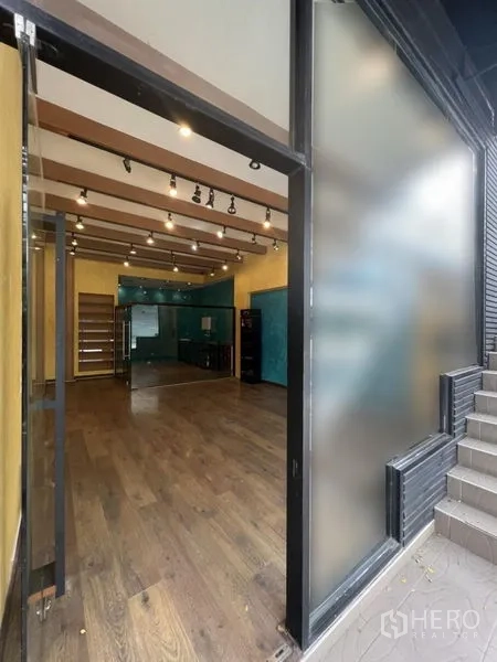 零售空间 出租在Watthana, Bangkok - 从入口望向室内的视角，见到磨砂玻璃侧板、木地板及外部台阶。