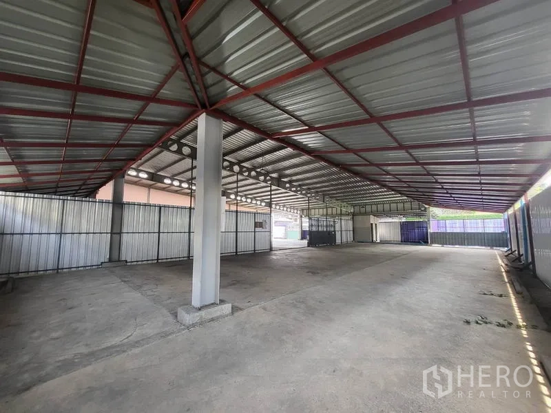 Warehouse for rent in Din Daeng, Bangkok - Covered loading bay with red steel beams, wide spans and ventilated metal walls.
