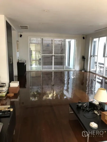 Detached House for rent in Chatuchak, Bangkok - Spacious living room with glossy hardwood floors and large windows opening to the patio.