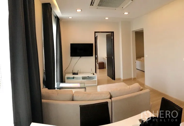 Condominium for sale in Khan Na Yao, Bangkok - Cozy living room with beige sofa facing wall-mounted TV and recessed lighting.