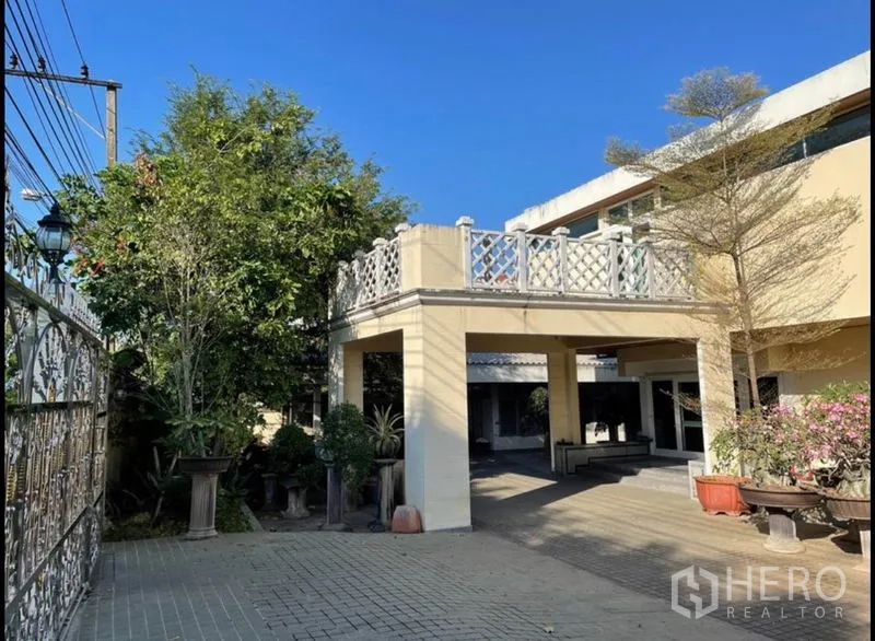 Detached House for rent in Khlong Toei, Bangkok - Exterior view showing raised terrace, columned carport and paved courtyard of the house.