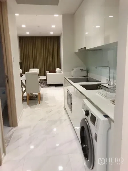 คอนโด ให้เช่าในWatthana, Bangkok - ครัวสไตล์แกลเลอรี่โทนขาว พร้อมเครื่องซักผ้าและตู้บิลท์อิน เชื่อมต่อสู่โซนนั่งเล่นและรับประทานอาหาร