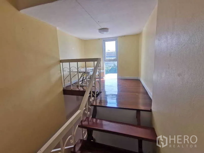 ทาวน์เฮาส์ ให้เช่าในChatuchak, Bangkok - โถงบันได พื้นไม้ พร้อมแสงธรรมชาติจากประตูด้านหลัง.