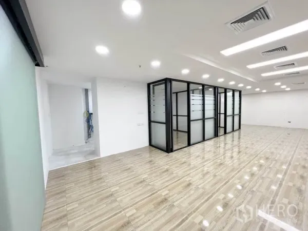 办公空间 出租在Phaya Thai, Bangkok - 开放工位区对着黑框磨砂玻璃会议室，顶面灯光充足。