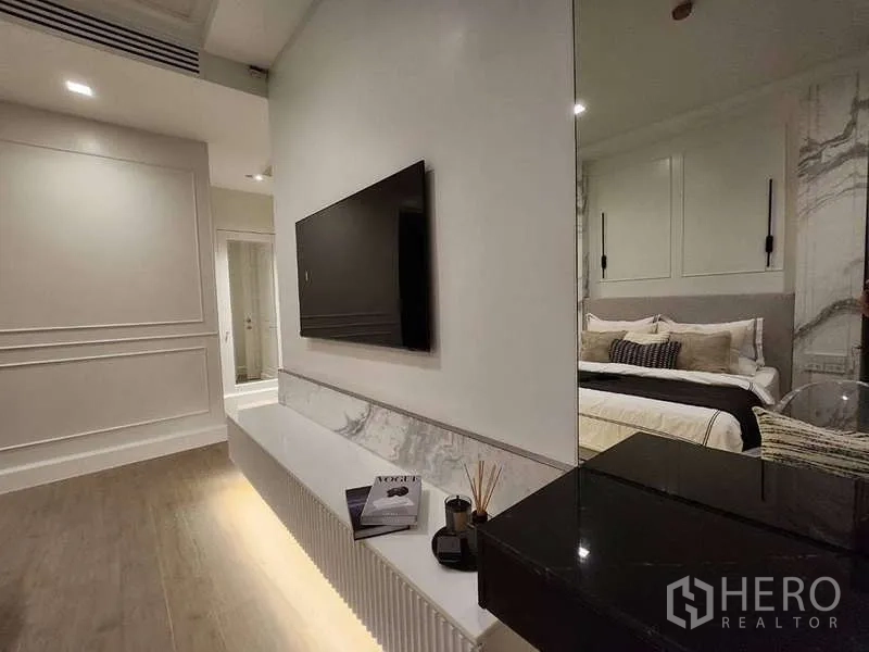 Condominium for sale in Watthana, Bangkok - Bedroom media wall with mounted TV and underlit console shelf.