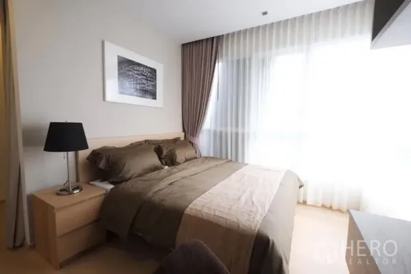 公寓 出租在Watthana, Bangkok - 主卧采光充足，木质床与床头灯，落地窗配纱帘的通罗公寓