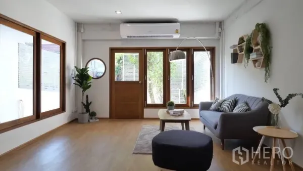 ทาวน์เฮาส์ ให้เช่าในKhlong Toei, Bangkok - ห้องนั่งเล่นสว่าง พื้นไม้ โซฟา หน้าต่างบานกว้าง และแอร์แขวนผนัง