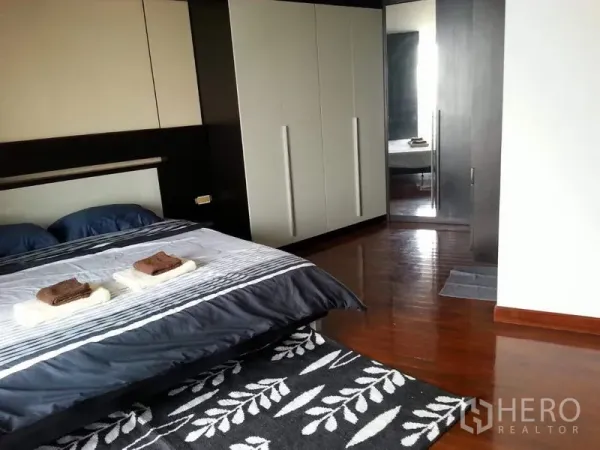 公寓 出租或出售在Pathum Wan, Bangkok - 主卧宽敞，内置衣柜、大镜面与木地板，采光良好。