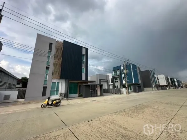 货栈 出售在Pathum Thani - 多栋现代仓库沿宽阔混凝土道路排列，阴天街景。
