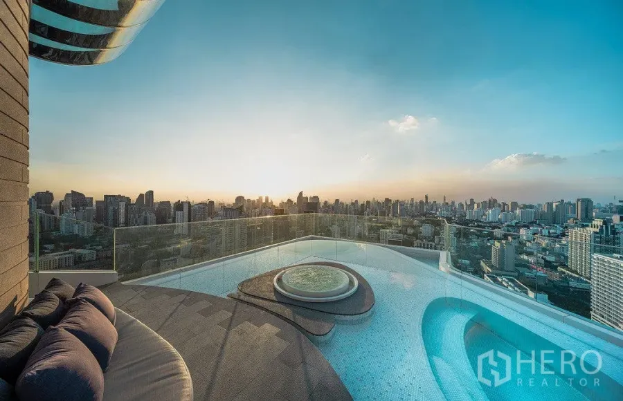 公寓 出租在Watthana, Bangkok - 日落下的屋顶无边际泳池与按摩池，眺望曼谷天际线的高层公寓景观。