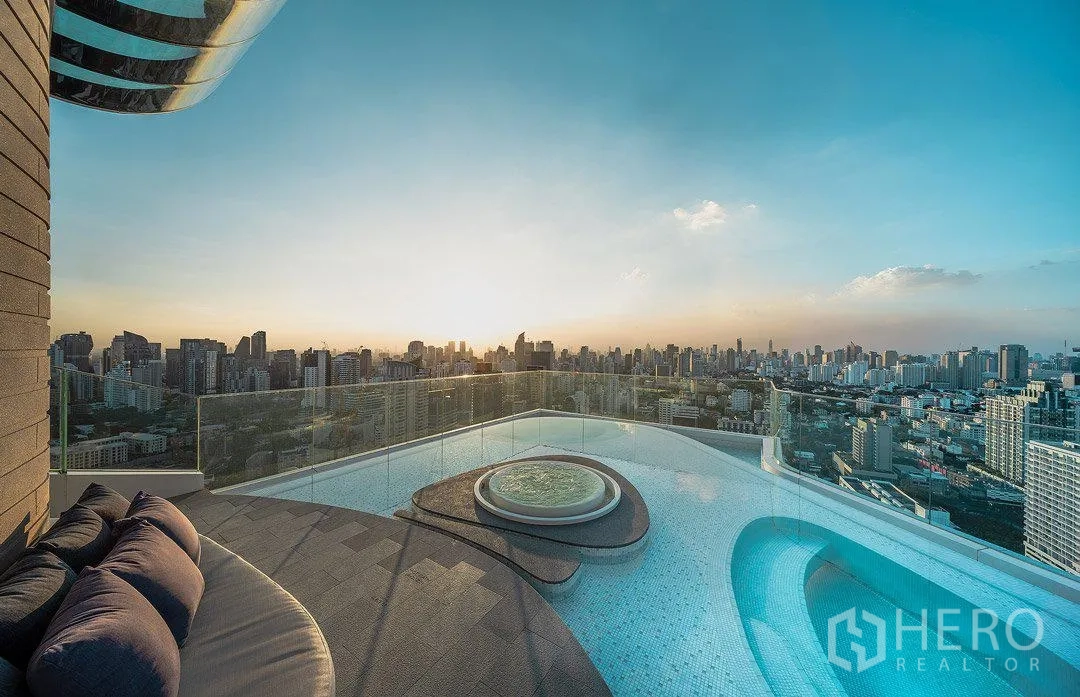 公寓 出租在Watthana, Bangkok - 日落下的屋顶无边际泳池与按摩池，眺望曼谷天际线的高层公寓景观。