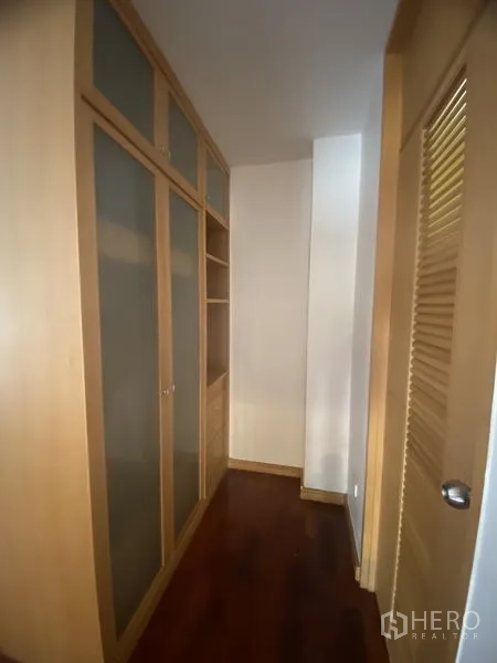 Condominium for rent - Hallway storage with tall built-in closets, frosted glass panels and wooden flooring.
