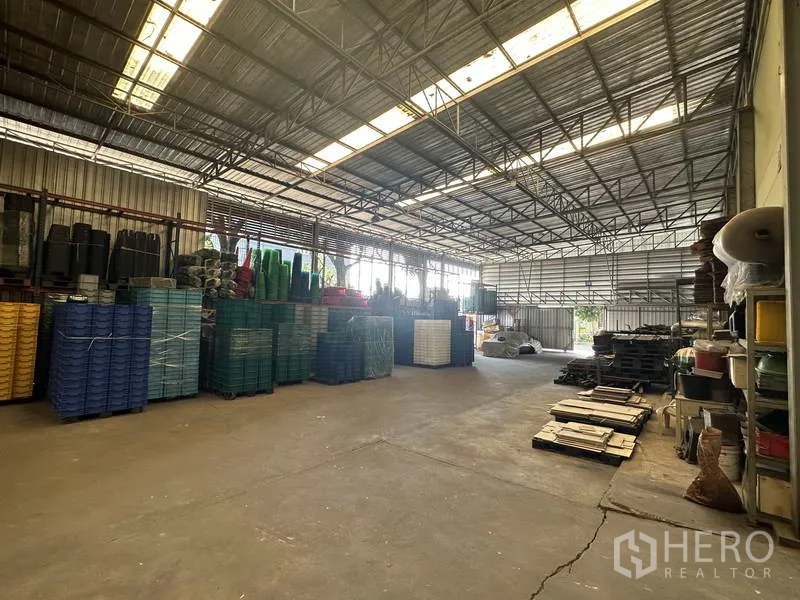 Factory for rent or sale in Khlong Luang, Pathum Thani - Storage hall with stacked plastic bins under a steel truss roof.