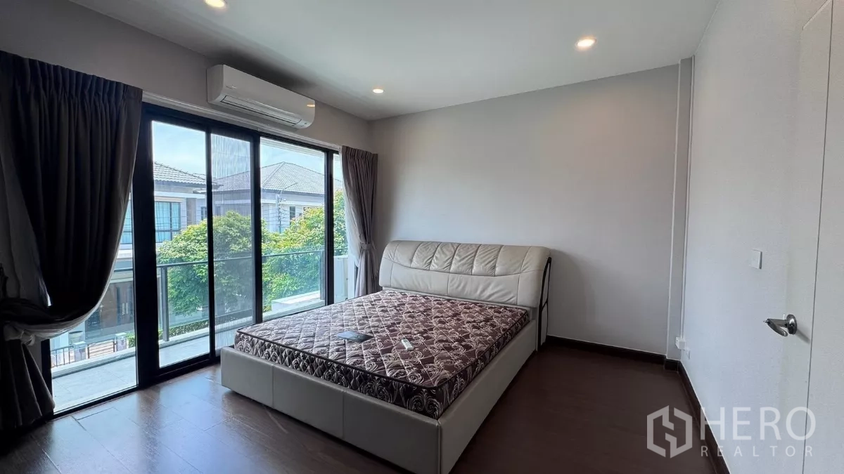 บ้าน ให้เช่าหรือขายในSaphan Sung, Bangkok - ห้องนอนใหญ่เปิดออกสู่ระเบียงด้วยประตูกระจกบานเลื่อน มีเครื่องปรับอากาศและวิวต้นไม้.