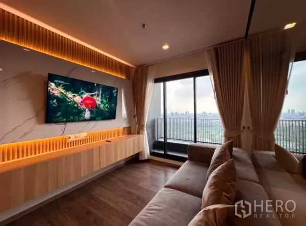 Condominium for rent in Chatuchak, Bangkok - TV feature wall with warm lighting facing a balcony overlooking Chatuchak Park skyline.