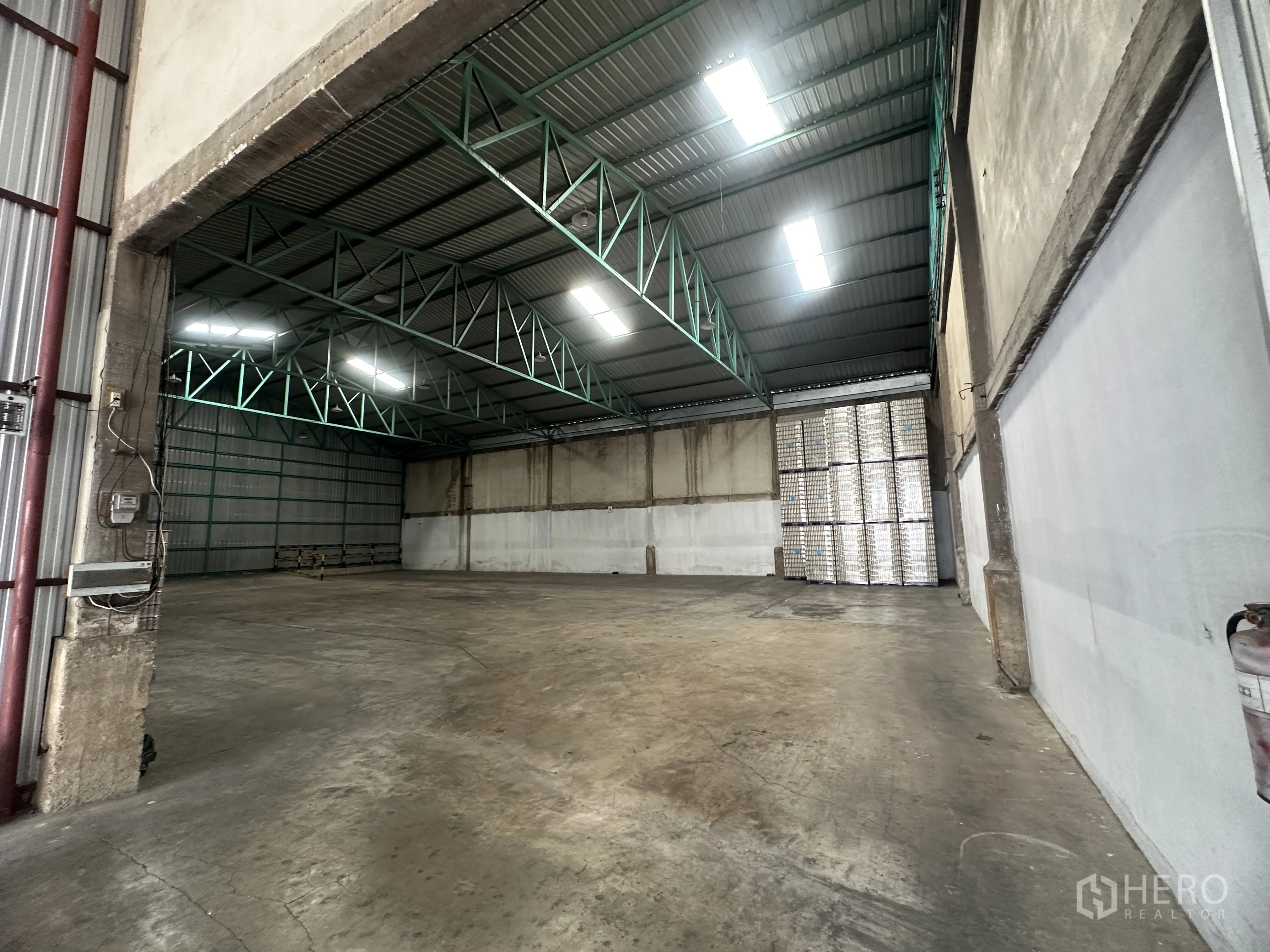 货栈 for rent in Mueang Pathum Thani, Pathum Thani - 从出入口望向开阔仓储区，金属板墙体与加固地坪清晰可见。