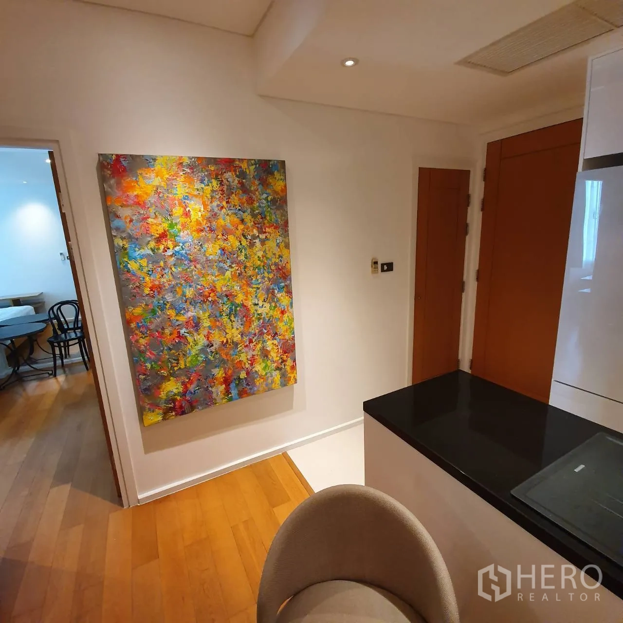 Condominium for rent in Watthana, Bangkok - Hallway view of sleek kitchen counter and a vivid abstract painting on a white wall.
