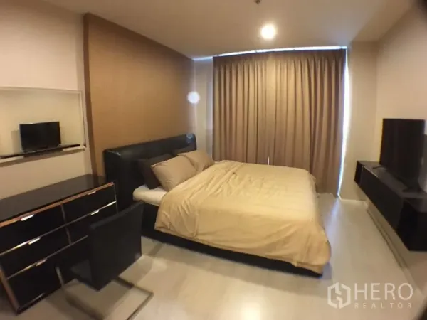 Condominium for rent in Sathon, Bangkok - Master bedroom with queen bed, dresser, TV and floor-to-ceiling curtains.