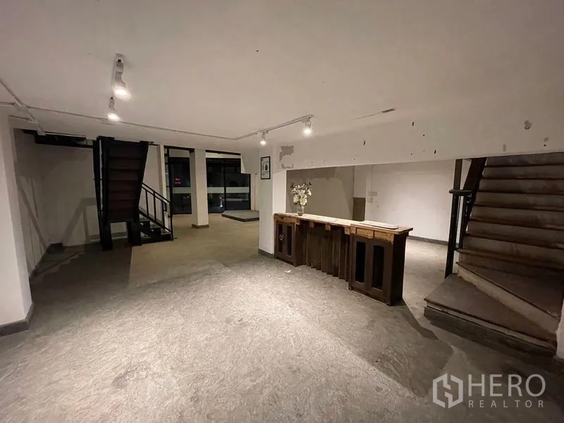 店屋 出租在Suan Luang, Bangkok - 开放式展厅，双楼梯布局，射灯照明，玻璃门面与木质接待台。