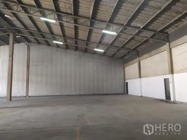 Warehouse for rent in Samut Prakan - Open-plan storage hall with corrugated metal wall panels and clear-span roof.