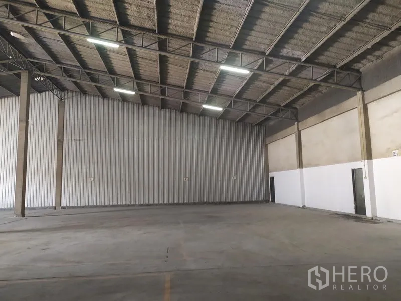 Warehouse for rent in Samut Prakan - Open-plan storage hall with corrugated metal wall panels and clear-span roof.