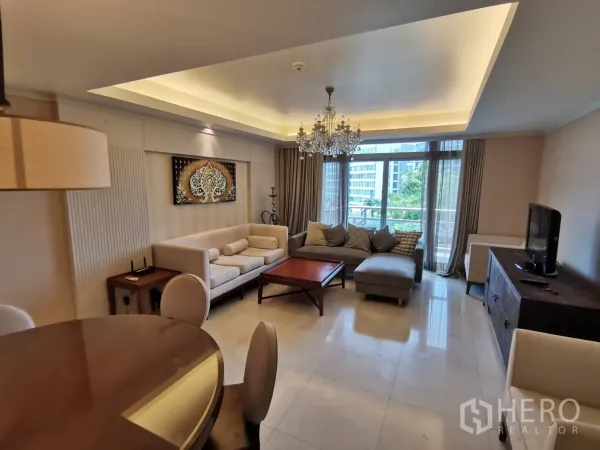 คอนโด ให้เช่าในPathum Wan, Bangkok - ห้องนั่งเล่นกว้าง เพดานหลุมติดโคมระย้า โซฟาเข้ามุม ประตูสไลด์ออกระเบียง มองเห็นต้นไม้และวิวเมือง