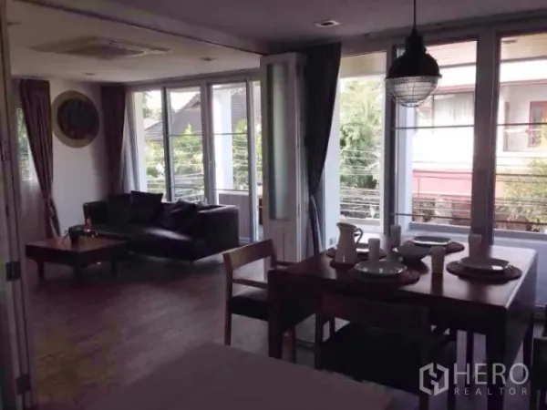 公寓 出租在Huai Khwang, Bangkok - 客餐厅连接阳台的大玻璃门，可见绿意社区景观。